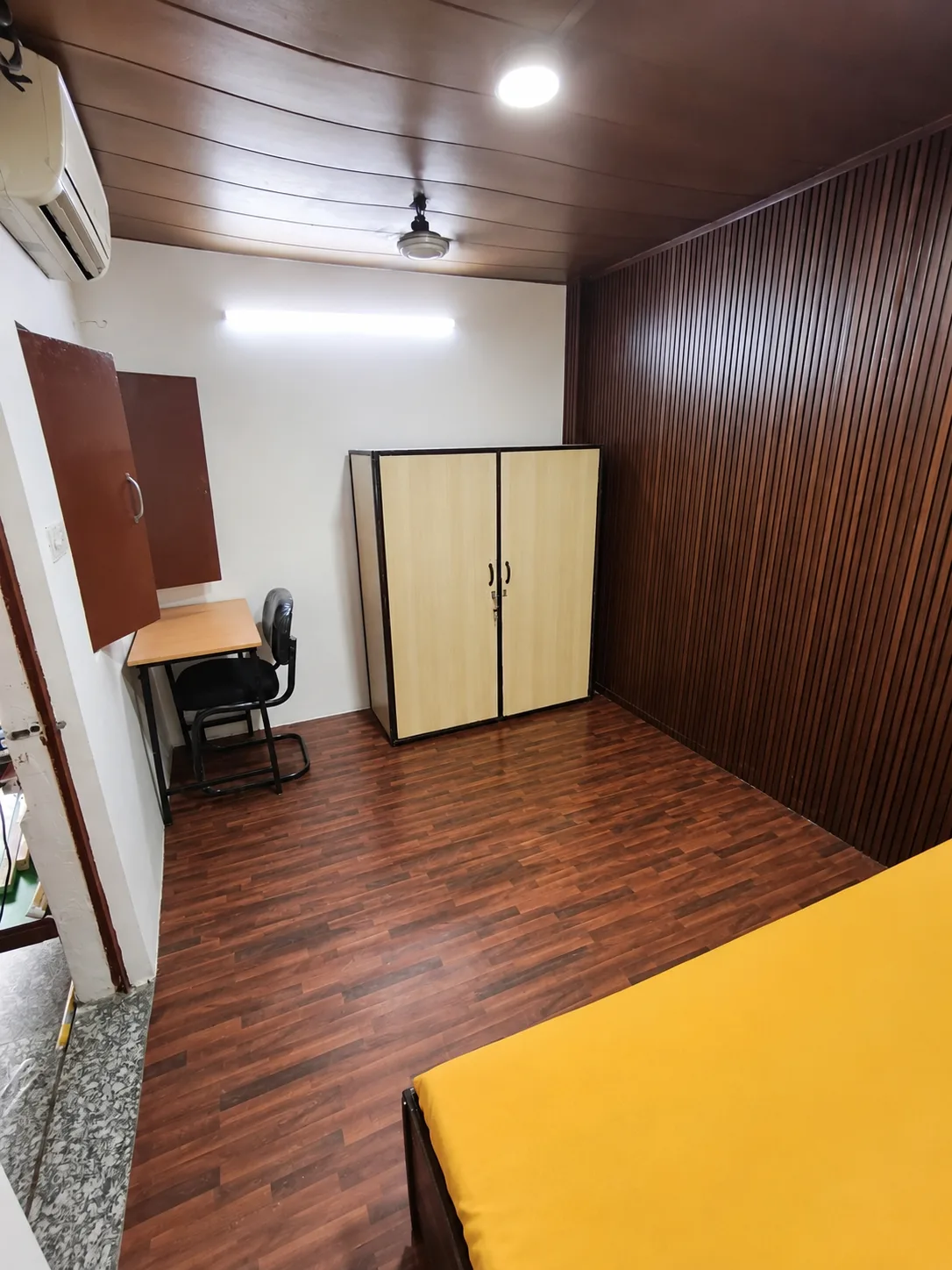 Single room at Duhomes boys PG Kamla Nagar, bed with wooden panel wall